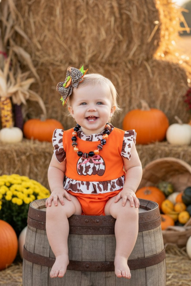 Cow printed pumpkin baby bodysuit .